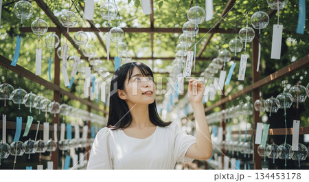 吊り下げられたたくさんの風鈴の下に立つ女性 吊り下げられたたくさんの風鈴の下に立つ女性 134453178