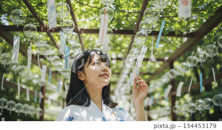 吊り下げられたたくさんの風鈴の下に立つ女性 134453179