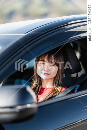 車の助手席に乗り楽しそうにするロングヘアの若い女性 134454140