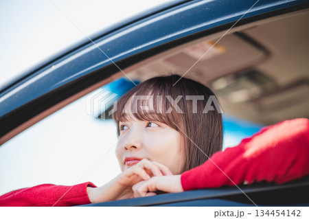 車の助手席に乗り楽しそうにするロングヘアの若い女性 車の助手席に乗り楽しそうにするロングヘアの若い女性 134454142