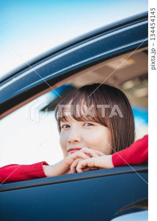 車の助手席に乗り楽しそうにするロングヘアの若い女性 車の助手席に乗り楽しそうにするロングヘアの若い女性 134454145