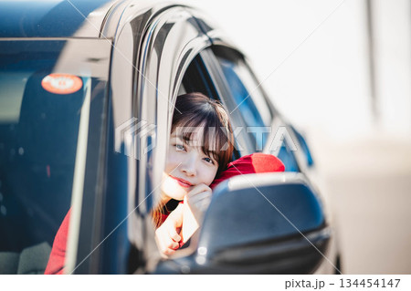 車の助手席に乗り楽しそうにするロングヘアの若い女性 車の助手席に乗り楽しそうにするロングヘアの若い女性 134454147