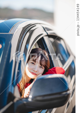 車の助手席に乗り楽しそうにするロングヘアの若い女性 車の助手席に乗り楽しそうにするロングヘアの若い女性 134454149
