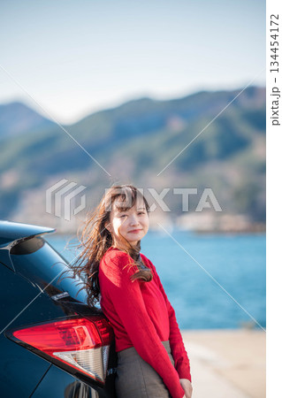 海辺で車に寄りかかり立つ女性 134454172