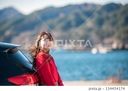 海辺で車に寄りかかり立つ女性 134454174