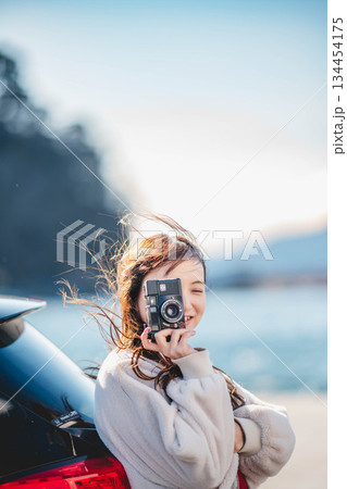 海辺で車に寄りかかり立つ女性 134454175