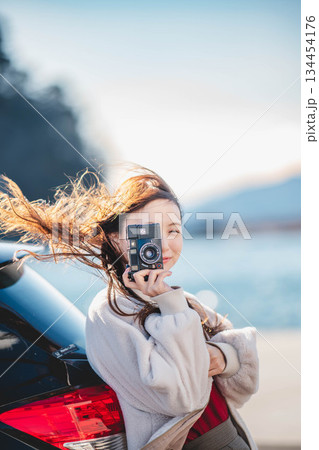 海辺で車に寄りかかり立つ女性 134454176
