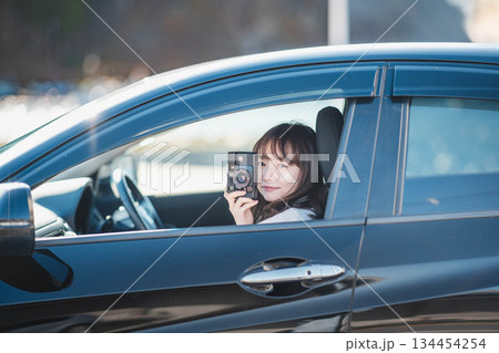 車の助手席に座りカメラを構える若いロングヘアの女性 134454254