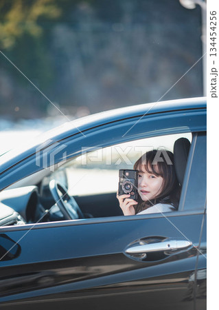 車の助手席に座りカメラを構える若いロングヘアの女性 車の助手席に座りカメラを構える若いロングヘアの女性 134454256