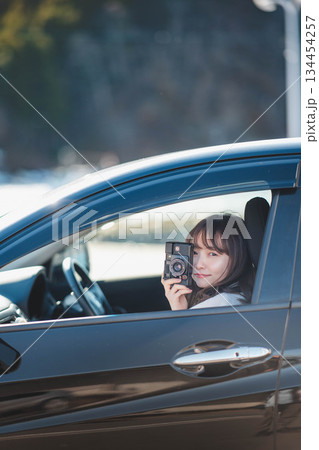車の助手席に座りカメラを構える若いロングヘアの女性 134454257