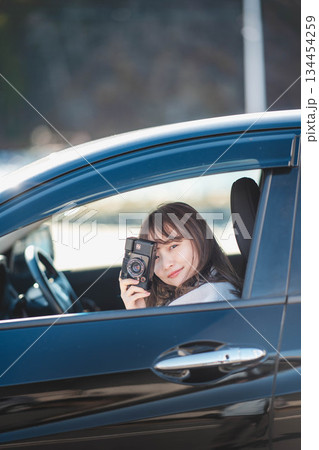 車の助手席に座りカメラを構える若いロングヘアの女性 車の助手席に座りカメラを構える若いロングヘアの女性 134454259