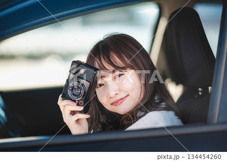 車の助手席に座りカメラを構える若いロングヘアの女性 車の助手席に座りカメラを構える若いロングヘアの女性 134454260
