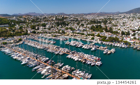 Aerial view of yacht marina in Bodrum, Turkey. Luxury boats and yachts docked in harbor with coastal city and hills in background, popular travel destination. Aerial view of yacht marina in Bodrum, Turkey. Luxury boats and yachts docked in harbor with coastal city and hills in background, popular travel destination. 134454261