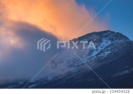 Slavkovsky peak in High Tatras National Park, Slovakia, Europe. A tranquil mountain peak shrouded in mist under a vibrant sky, where nature's artistry unfolds in a mesmerizing display of colors. 134454328