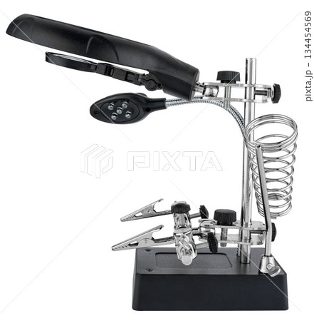 Magnifying glass with clamps for jewelry and electronic soldering. On a white background in isolation. Magnifying glass with clamps for jewelry and electronic soldering. On a white background in isolation. 134454569