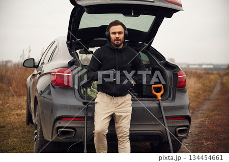 Against the car. Man is with metal detector in the field Against the car. Man is with metal detector in the field 134454661