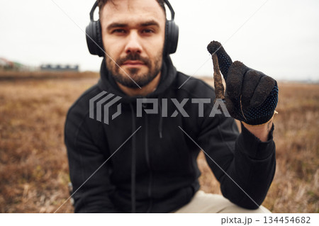 Man sapper in headphones is holding old bullet that he found in the field Man sapper in headphones is holding old bullet that he found in the field 134454682