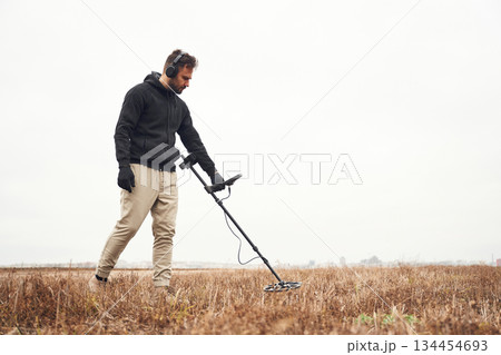 Cloudy white background. Man is with metal detector in the field Cloudy white background. Man is with metal detector in the field 134454693
