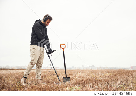 Cloudy white background. Man is with metal detector in the field Cloudy white background. Man is with metal detector in the field 134454695