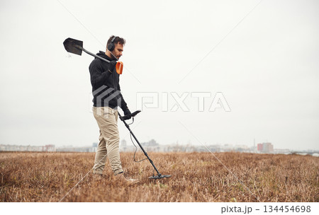 Holding a shovel. Man is with metal detector in the field Holding a shovel. Man is with metal detector in the field 134454698