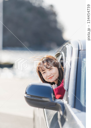 車に乗りながら座席から身を乗り出す赤いニットの若い女性 134454739