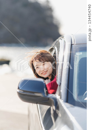 車に乗りながら座席から身を乗り出す赤いニットの若い女性 車に乗りながら座席から身を乗り出す赤いニットの若い女性 134454740