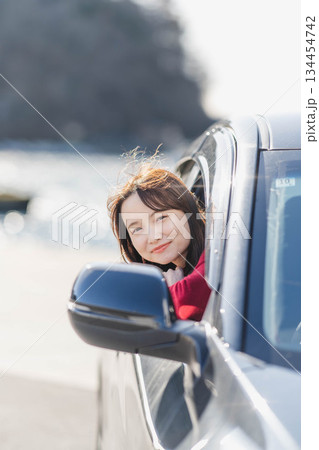 車に乗りながら座席から身を乗り出す赤いニットの若い女性 車に乗りながら座席から身を乗り出す赤いニットの若い女性 134454742