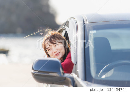 車に乗りながら座席から身を乗り出す赤いニットの若い女性 134454744