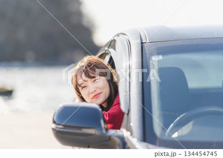 車に乗りながら座席から身を乗り出す赤いニットの若い女性 134454745