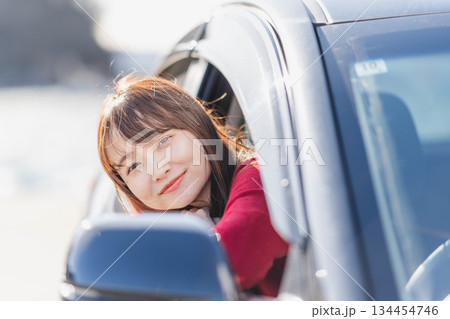 車に乗りながら座席から身を乗り出す赤いニットの若い女性 車に乗りながら座席から身を乗り出す赤いニットの若い女性 134454746