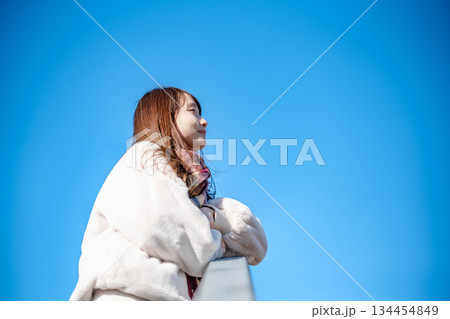 青空と白いコートのロングヘアの若い女性 青空と白いコートのロングヘアの若い女性 134454849
