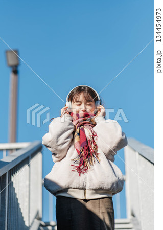 青空の下に立ち音楽を聴く笑顔の女の子 青空の下に立ち音楽を聴く笑顔の女の子 134454973
