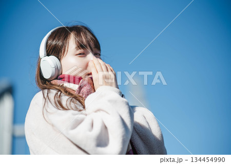 青空の下に立ち音楽を聴く笑顔の女の子 青空の下に立ち音楽を聴く笑顔の女の子 134454990