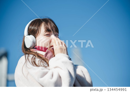 青空の下に立ち音楽を聴く笑顔の女の子 青空の下に立ち音楽を聴く笑顔の女の子 134454991