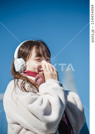 青空の下に立ち音楽を聴く笑顔の女の子 青空の下に立ち音楽を聴く笑顔の女の子 134454994