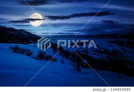 winter in mountainous countryside at night. gorgeous cloudy sky over the snow covered hills in full moon light. wide mountain ridge in a far distance. backdrop for fiction art or mystery concepts winter in mountainous countryside at night. gorgeous cloudy sky over the snow covered hills in full moon light. wide mountain ridge in a far distance. backdrop for fiction art or mystery concepts 134455085