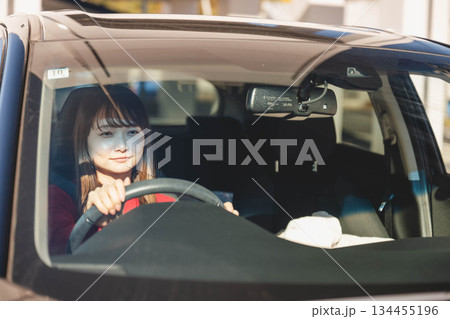 晴れた日に車を運転する若いロングヘアの女性 晴れた日に車を運転する若いロングヘアの女性 134455196