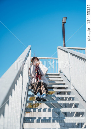 階段に座って空を見上げる若い女性 134455322