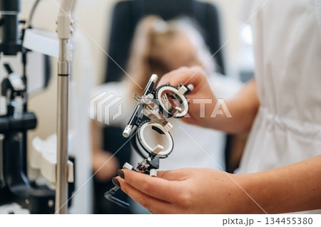Close up view of female doctor's hands that are holding ophthalmologist glasses 134455380