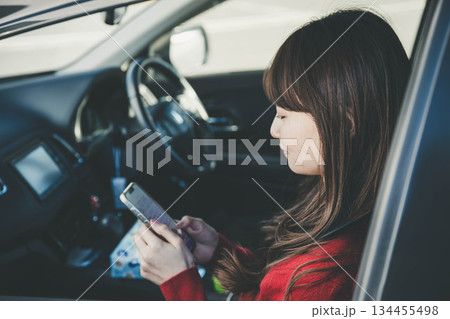 助手席でスマートフォンを操作する若い女性 助手席でスマートフォンを操作する若い女性 134455498