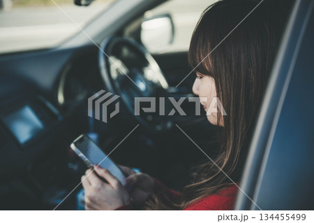 助手席でスマートフォンを操作する若い女性 助手席でスマートフォンを操作する若い女性 134455499