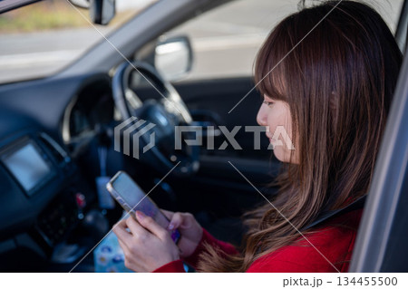 助手席でスマートフォンを操作する若い女性 助手席でスマートフォンを操作する若い女性 134455500