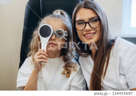 Helping, covering the eye. Little girl at the ophthalmologist clinic with doctor 134455697