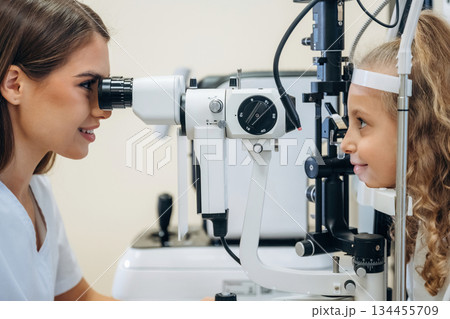 View from the side. Little girl at the ophthalmologist clinic with doctor 134455709