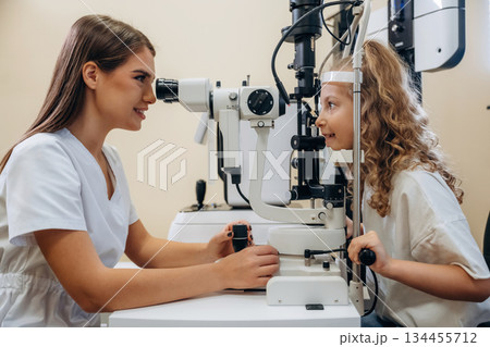 View from the side. Little girl at the ophthalmologist clinic with doctor 134455712