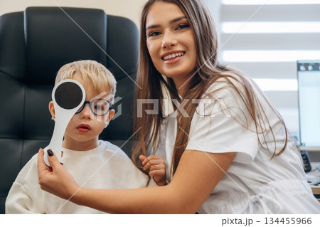 Covering the eye. Little boy is having check up in the ophthalmologist cabinet 134455966