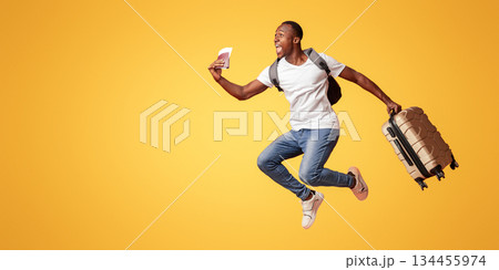 Finally vacation. Young happy black man with suitcase, backpack, passport and flight tickets jumping up orange studio background. Excited african american guy running towards copy space Finally vacation. Young happy black man with suitcase, backpack, passport and flight tickets jumping up orange studio background. Excited african american guy running towards copy space 134455974