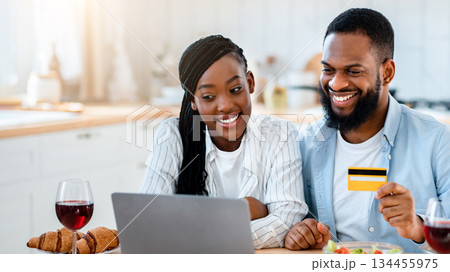 Food Ordering. Happy Black Spouses Using Laptop And Card In Kitchen, Making Online Delivery Order With Computer, Sitting At Table At Home And Enjoying Internet Purchases, Free Space Food Ordering. Happy Black Spouses Using Laptop And Card In Kitchen, Making Online Delivery Order With Computer, Sitting At Table At Home And Enjoying Internet Purchases, Free Space 134455975