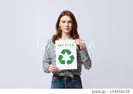 Recycling Concept. Young Beautiful Lady Demonstrating Placard With Green Recycle Sign, Millennial Eco-Friendly Nature-Lover Woman Standing Over Grey Studio Background, Looking At Camera, Copy Space Recycling Concept. Young Beautiful Lady Demonstrating Placard With Green Recycle Sign, Millennial Eco-Friendly Nature-Lover Woman Standing Over Grey Studio Background, Looking At Camera, Copy Space 134456226