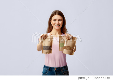 Eco Food Storing. Positive Young Lady Holding Three Kraft Paper Doypack Bags With Weight Groceries, Smiling Millennial Woman Choosing Biodegradable Ziplock Packs, Posing Over Light Grey Background Eco Food Storing. Positive Young Lady Holding Three Kraft Paper Doypack Bags With Weight Groceries, Smiling Millennial Woman Choosing Biodegradable Ziplock Packs, Posing Over Light Grey Background 134456236